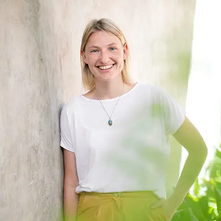 Photo of Jonnemei, standing next to a wall.